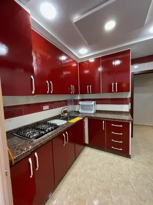 a kitchen with red cabinets and a stove top oven at Appartement T4 in Taza