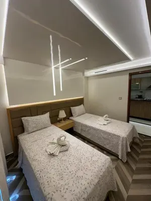 a room with two beds with white sheets and a window at Appartement T4 in Taza