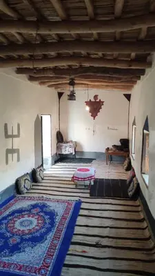 a living room with a rug on the floor and a room with a bed at Tamrdulte in Tinerhir