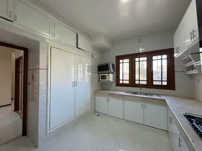 a large kitchen with white cabinets and a window at Appartement Spacieux résidence privée surveiller in Fès
