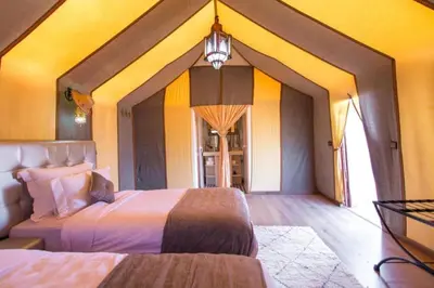 a bedroom with two beds and a yellow wall at Sahara Moon Camp in Merzouga