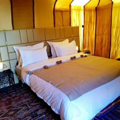 a bedroom with a large bed with white pillows at Sahara Moon Camp in Merzouga