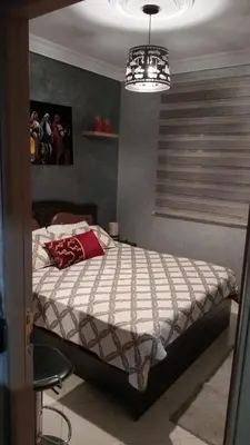 a bedroom with a bed and a chandelier at Appartement Conviviable Et Chaleureux in Oulad Akkou