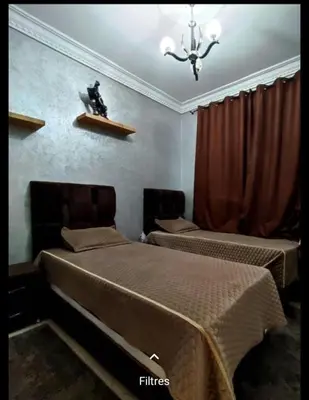 a bedroom with two beds and a chandelier at Appartement Conviviable Et Chaleureux in Oulad Akkou