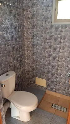 a bathroom with a toilet and a tiled wall at appartement lamia in Azrou