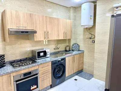 a kitchen with a stove and a sink and a microwave at Charmant appartement meublé avec Wifi Fibre 100Mo in Fès