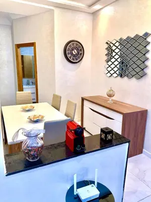 a dining room with a table and a clock on the wall at Charmant appartement meublé avec Wifi Fibre 100Mo in Fès