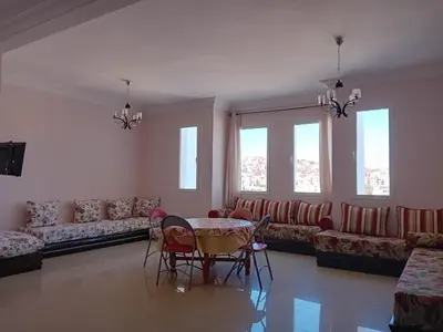 a living room with a table and chairs and a couch at Al massira fnideq in Oulad Akkou