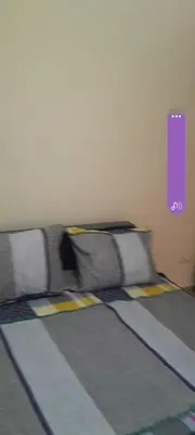 a bed in a room with a purple sign on the wall at Al massira fnideq in Oulad Akkou