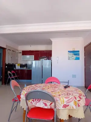a kitchen with a table with chairs and a refrigerator at Al massira fnideq in Oulad Akkou