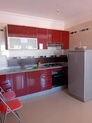 a kitchen with red cabinets and a white refrigerator at Al massira fnideq in Oulad Akkou