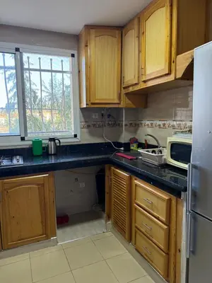 a kitchen with wooden cabinets and a sink and a refrigerator at Cozy & Affordable Family Apartment for married couples only in Ifrane
