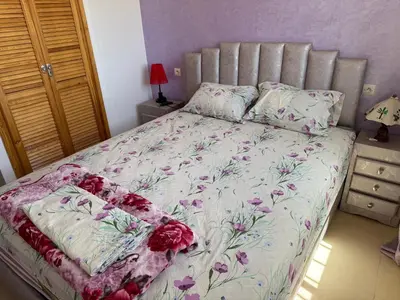 a bed with a floral bedspread and pillows on it at Cozy & Affordable Family Apartment for married couples only in Ifrane