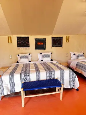 a bedroom with two beds and a blue bench at ALQADAR - Desert Lux Camp in Merzouga
