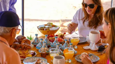 a group of people sitting around a table with food at ALQADAR - Desert Lux Camp in Merzouga