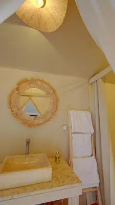 a bathroom with a sink and a mirror and a chair at ALQADAR - Desert Lux Camp in Merzouga