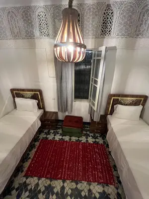 a room with two beds and a chandelier at Dar Latifa in Fès