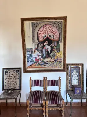 a room with two chairs and a painting on the wall at Apparemment fes la momie in Fès