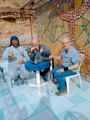 three men sitting at a table in front of a wall at Auberge baddou amougar in Amouguer