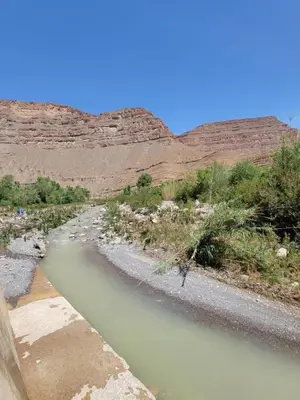 a river in the middle of a desert with mountains at Auberge baddou amougar in Amouguer