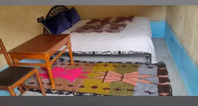 a bedroom with a bed with a desk and a table at Auberge baddou amougar in Amouguer