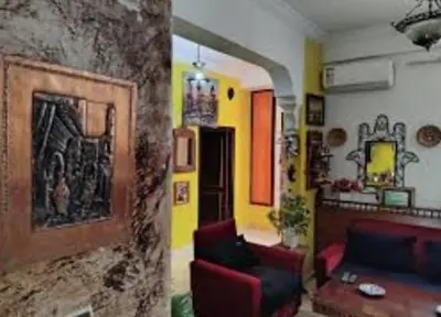 a living room with two red chairs and a stone wall at Hotel ouelfa in Oulad Akkou