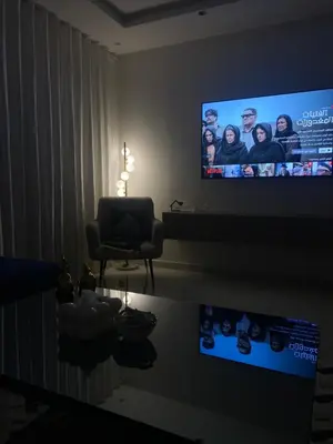a living room with a flat screen tv and a chair at شقة فخمة in Ifrane
