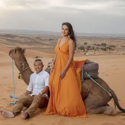 a man and a woman sitting on a camel in the desert at Sahara serenity camp in Merzouga