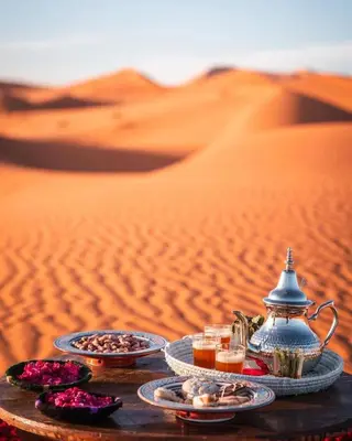 a table in the desert with food and drinks at Sahara serenity camp in Merzouga