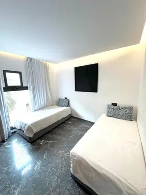 a room with two beds and a flat screen tv at Rooftop avec Piscine privée - 2 chambres - Marrakech in Oulad Akkou