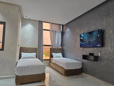 a bedroom with two beds and a tv on the wall at appartement moderne khenifra 2 in Khenifra