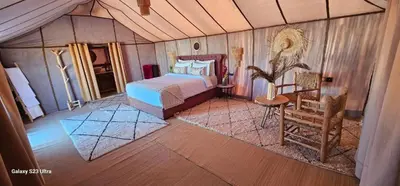 a bedroom with a bed and a chair in a room at Sahara Classic Luxury Camp in Merzouga