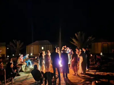 a group of people walking around at night at Sahara Classic Luxury Camp in Merzouga