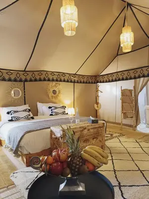 a bedroom with a bed with a bowl of fruit on a table at Sahara Classic Luxury Camp in Merzouga