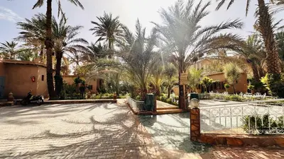 a courtyard with palm trees and a fence at Nana Diafa - Zagora Guest House & Restaurant in Zagora