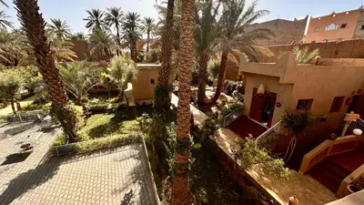 an outdoor courtyard with palm trees and a building at Nana Diafa - Zagora Guest House & Restaurant in Zagora