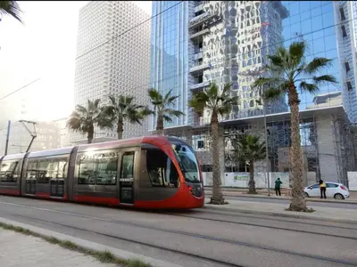 a red tram on a city street with palm trees at CFC - Douceur et luminosité in Oulad Akkou