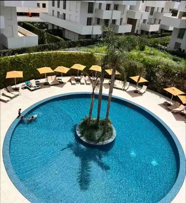 a swimming pool with a palm tree and umbrellas at CFC - Douceur et luminosité in Oulad Akkou