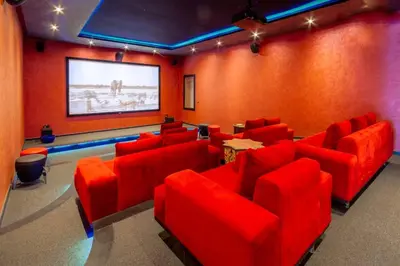 a cinema room with red chairs and a projection screen at Palais pyar in Najem