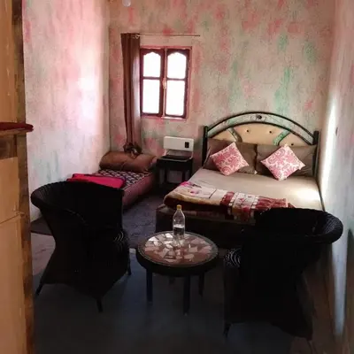 a bedroom with a bed and chairs and a table at Café nour dar ait ben haddou in Taskoukte