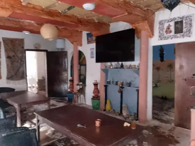 a living room with a table and a tv on the wall at Café nour dar ait ben haddou in Taskoukte
