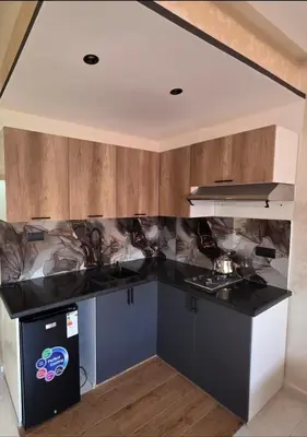 a kitchen with black counter tops and wooden cabinets at Appartement luxe 3 in Khenifra