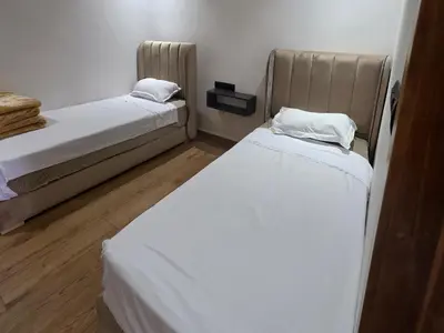 two beds in a small room with white sheets at Appartement luxe 3 in Khenifra