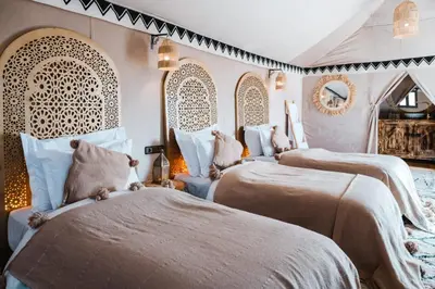 a bedroom with three beds and a mirror at Merzouga Toop Luxury Camp in Merzouga