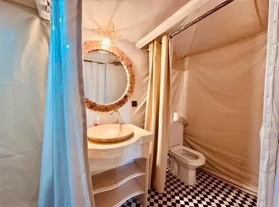 a bathroom with a sink and a mirror and a toilet at Merzouga Toop Luxury Camp in Merzouga