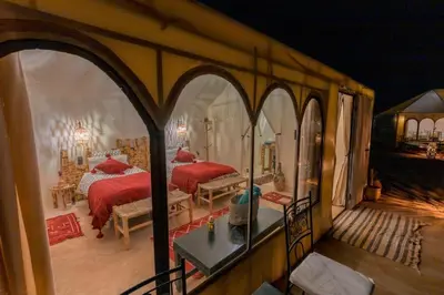 a bedroom with two beds in a room with arches at Merzouga Toop Luxury Camp in Merzouga