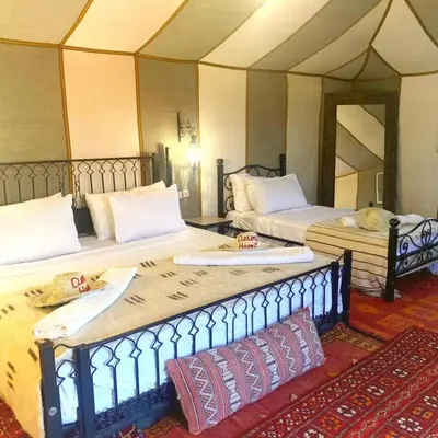 a room with two beds in a room with a tent at Merzouga Toop Luxury Camp in Merzouga