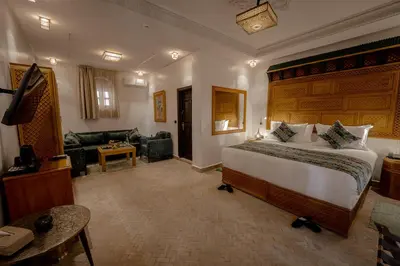 a bedroom with a large bed and a living room at Riad Joy in Fès