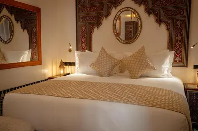 a bedroom with a large white bed with a mirror at Riad Joy in Fès