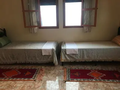 two beds in a room with two windows at Auberge Touristique Toubkal in Imlil